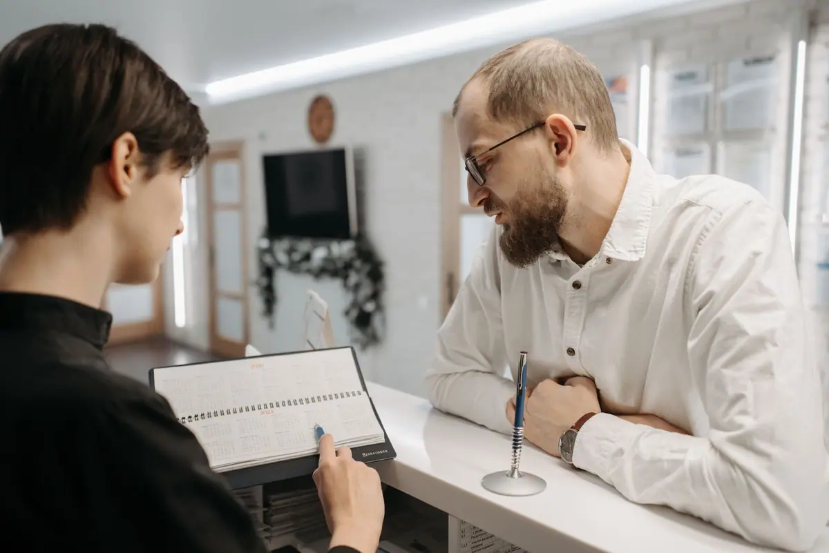 Una recepcionista de clínica revisando una cita con un visitante