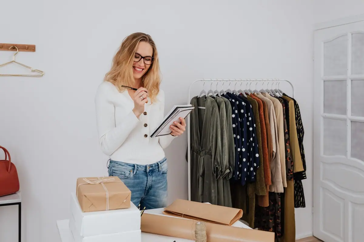 Una propietaria de boutique contando existencias entre percheros de ropa